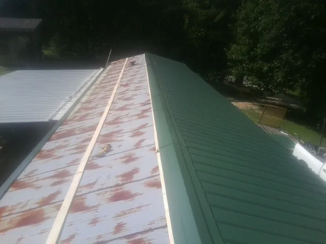 Old rusted panels beside newly installed green metal roofing — Wind Damage Roof Repair by Roofing Brothers in French Camp