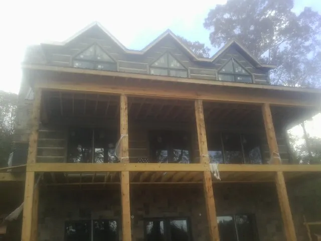 Dormers and porch framing on a large log home under construction — Roof Coating work by our crew in French Camp