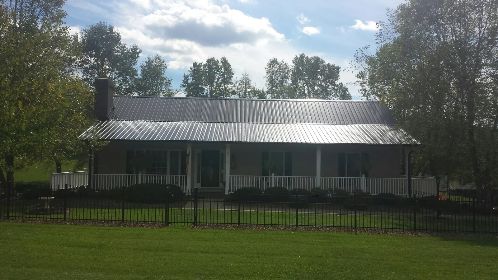 Gray metal roof on a brick ranch with a full width front porch — Gutter Guard Installation work by our crew in French Camp