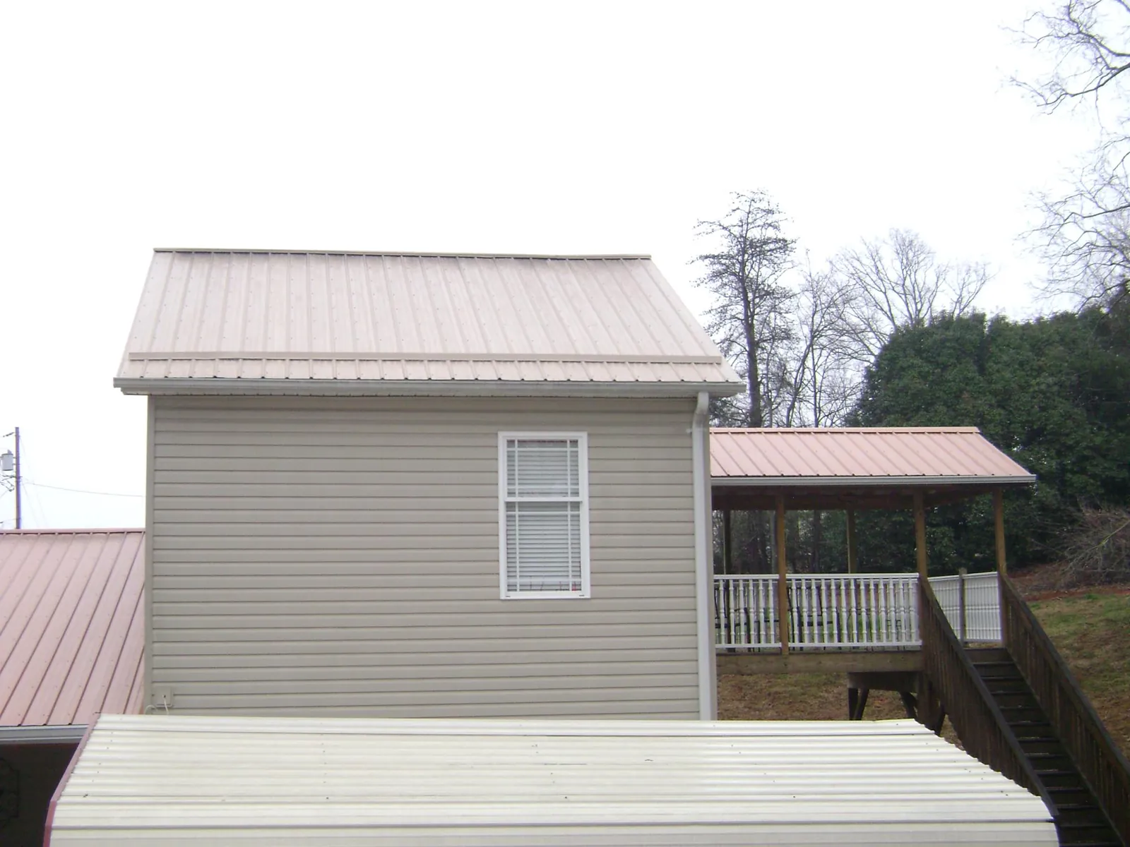 Tan metal roofs on a two story addition and attached porch, from a Roof Replacement job in French Camp